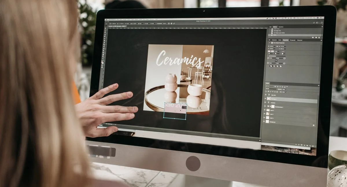 A graphic designer works on a ceramics promotion using Adobe Photoshop on an iMac.